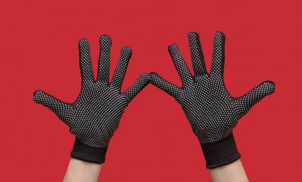Handen in zwart gecoate natuurlijke beschermende handschoenen. Op een rode achtergrond. — Stockfoto