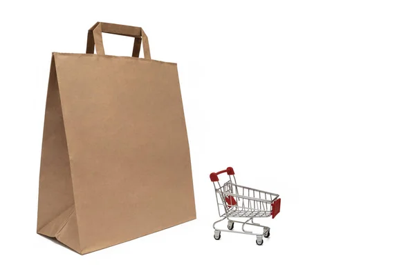 Бумажный пакет и тележка из супермаркета. Концепция продажи и покупки продукции. — стоковое фото