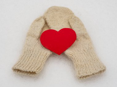 Beyaz kar üzerinde beyaz yün eldivenler. Kış giysileri Kırmızı bir kalp. Sevgililer Günü.