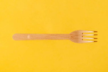 Wooden brown disposable tableware. Fork pattern. On a yellow background. Environmentally friendly product. Natural paper.