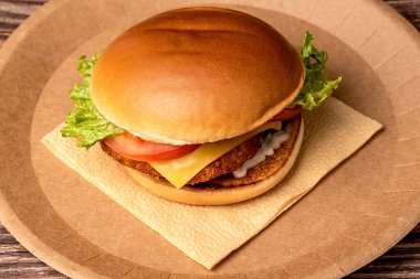 Hamburger tek kullanımlık kahverengi bir tabakta. Yakın plan. Lezzetli abur cubur.