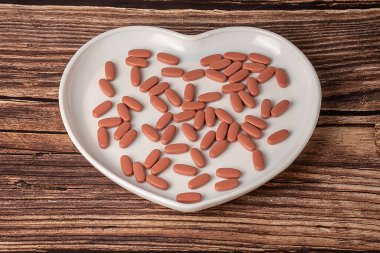 Kahverengi haplar, kalp şeklinde beyaz bir porselen tabakta yatar. Ahşap bir arka planda.