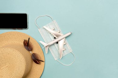 Uçakla yolculuk. Mavi arka planda bir model oluşturun. Şapka, uçak, gözlük, telefon.