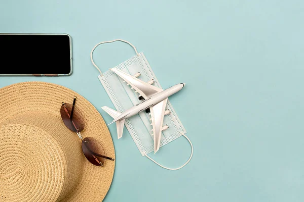 Traveling by plane. Mock up on a blue background. Hat, plane, glasses, phone.