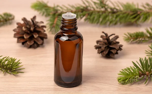Cosmetic oil. Needle oil. Alternative health medicine. Skin care. Cones and needles. On a wooden table.