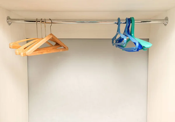 A házakban műanyag és fa akasztók lógnak egy új, üres szekrényben.. — Stock Fotó