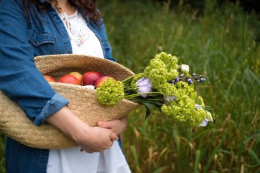 Elinde çiçek ve meyve dolu bir sepet tutan kız.
