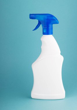 Beyaz plastik bir şişedeki cam temizleyicisinde mavi beyaz arka planda sprey var. Temizlik ve temizlik kavramı