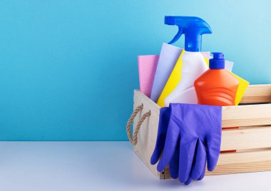 Mavi arka planda temizlik ürünleri olan ahşap sepet ve metin için yer. Temizlik ve temizlik kavramı