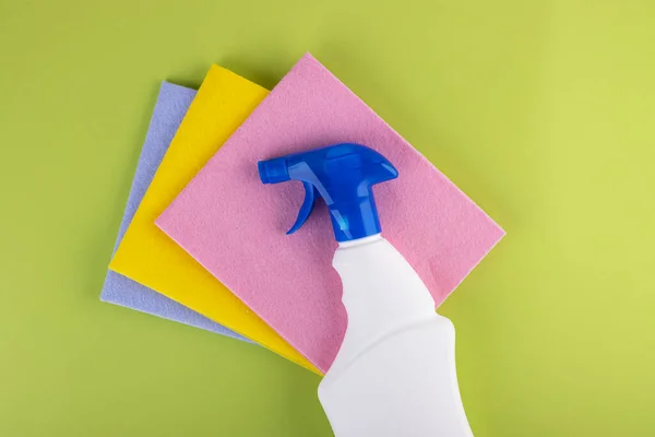 colored rags with cleaning agent for cleaning and cleanliness in the house on a green background. the concept of cleanliness and order