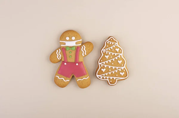 Christmas ginger man in a mask with a gingerbread tree. the concept of wearing a medical mask during a pandemic