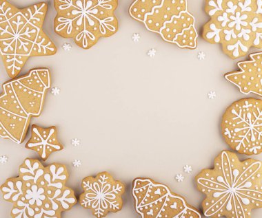 Yumuşak pastel arka planda zencefilli kek ve metin için yer var. Kar taneleri ve Noel ağaçları bir çember içinde serilmiştir.