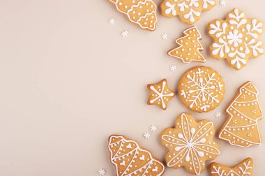 Yumuşak pastel arka planda zencefilli kek ve metin için yer var. Kar taneleri ve Noel ağaçları masaya saçılmış.