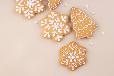 Yumuşak pastel arka planda zencefilli kek ve metin için yer var. Kar taneleri ve Noel ağaçları masaya saçılmış.