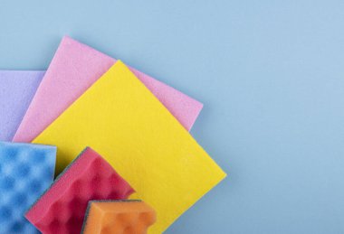 Güzel mavi bir arka planda renkli süngerler ve temiz bezler. Temizlik ve temizlik kavramı