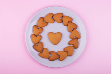 Pembe arka planda bir tabakta zencefilli kek kalpleri, üst manzara. Aşk ve aşık olma kavramı. Sevgililer Günü, Anneler Günü