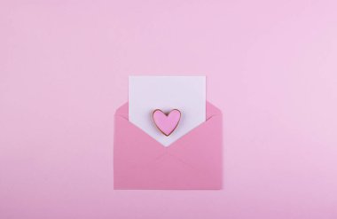 Pembe arka planda Sevgililer Günü için kırmızı kalpli bir zarf. Sevgi ve şefkat kavramı, Anneler Günü.
