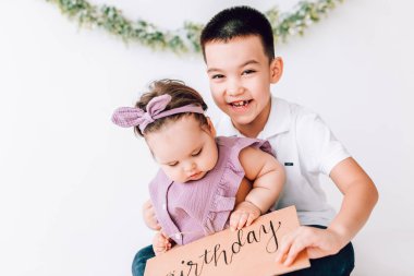 Neşeli çocuk gülüyor ve küçük kız kardeşine sarılıyor. Mutlu güçlü aile, çocuklar günü.