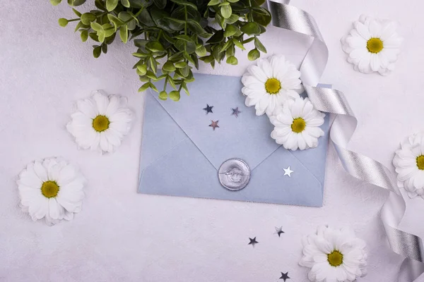 grey paper envelope with a wax seal and scattered white flowers on the background. background for Valentine\'s day, mother\'s day