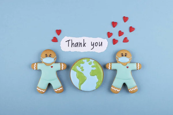 two gingerbread man medics in a mask with the inscription thank you and a lot of red hearts, gingerbread planet earth. thank you to the medical staff, the doctor, the nurses
