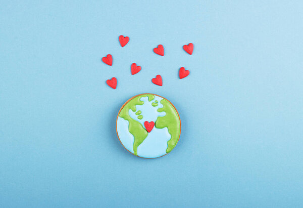Пряничный хлеб планеты Земля и много маленьких красных сердец на синем фоне. День Святого Валентина