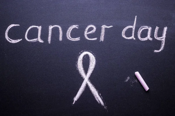 text of the day of the fight against cancer and Pink ribbon, made of chalk on black Board. women\'s health