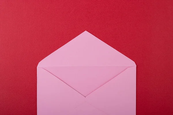 open empty pink envelope on red background with space for text. Valentine's day, mother's day