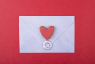 Üzerinde aşk damgası olan mavi bir zarf ve kırmızı arka planda kırmızı bir kalp. Aşk mektubu, sevgililer günü geçmişi, anneler günü.