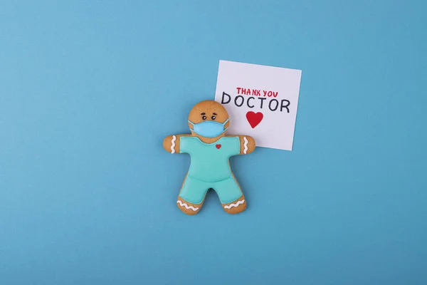 Gingerbread medic in a mask on a blue background. The coronavirus. Thank you to the doctors and nurses working in hospitals and fighting the coronavirus. Doctor-heroes