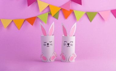 Kağıttan yapılmış şirin Paskalya tavşanları. Pembe pastel arka planda el yapımı. Mutlu Paskalyalar. Bahar Festivali