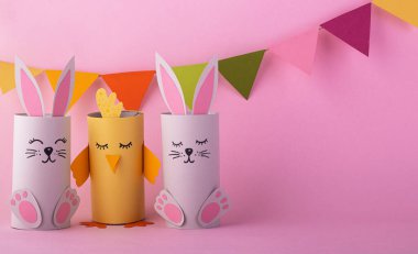 Kağıttan yapılmış tavşanlar ve kuşlar pembe arka planda süslemeli. Bayram konsepti, mutlu Paskalyalar.