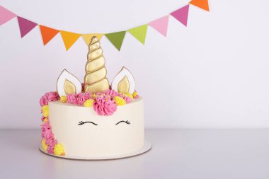 Güzel, narin, tek boynuzlu at doğum günü pastası beyaz bir masada.