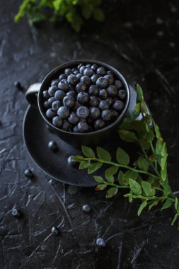 bir fincanda yabanmersini, siyah arka plan, ormanın hediyeleri.