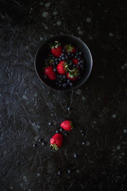 Çilek ve yaban mersini, siyah arka planda yiyecek.
