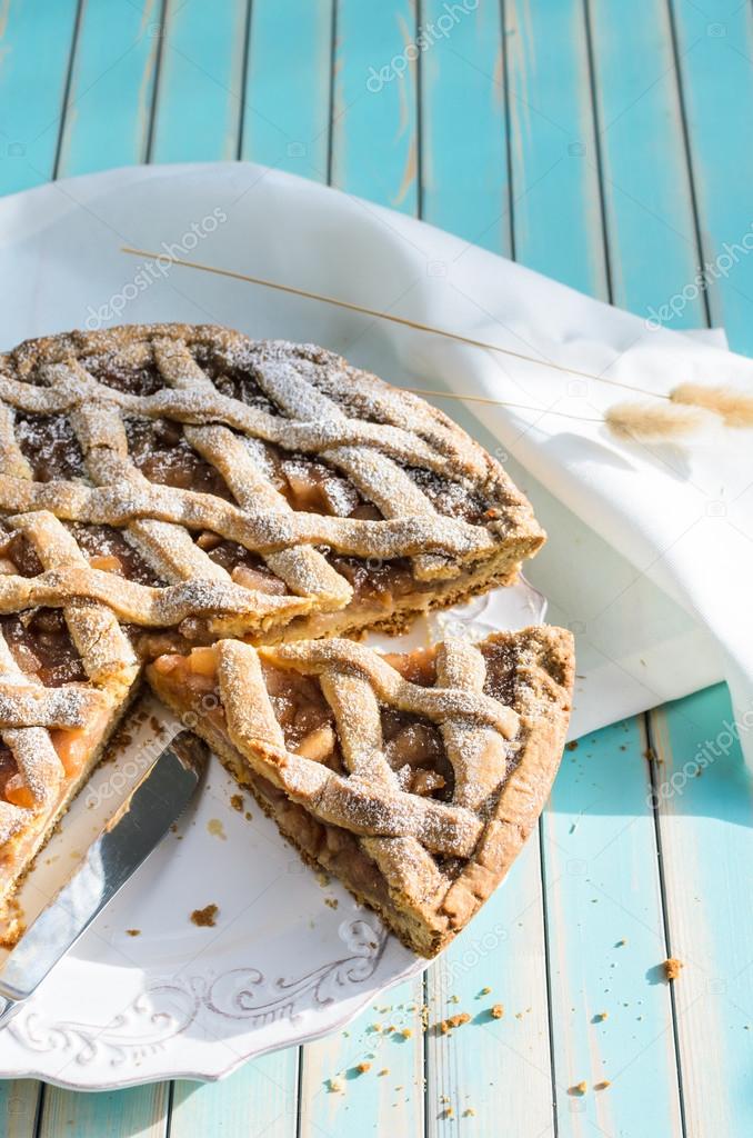 Homemade rustic apple tart pie on dish over wooden turquoise background