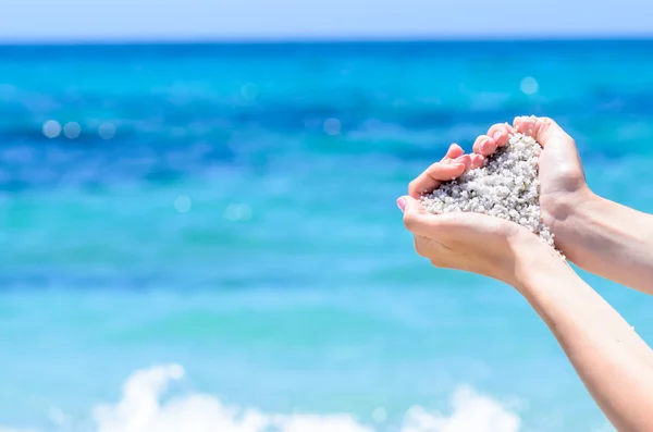 Närbild händer med sand i form av hjärta mot tropiska turkosa havet — Stockfoto