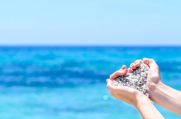 Nahaufnahme Hände mit Sand in Herzform gegen tropisches türkisfarbenes Meer — Stockfoto