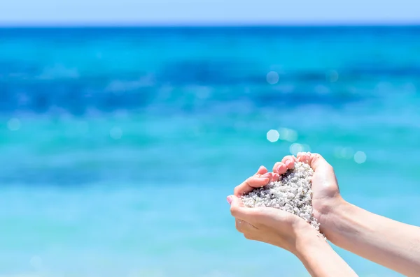 Nahaufnahme Hände mit Sand in Herzform gegen tropisches türkisfarbenes Meer — Stockfoto