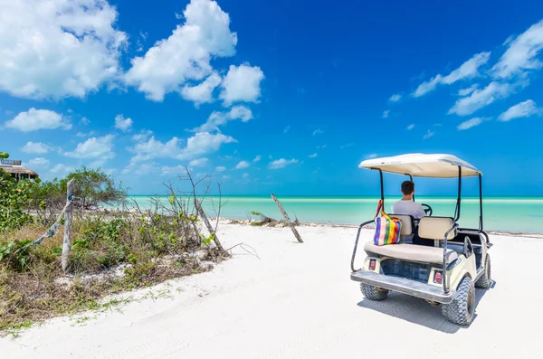 Ung man kör på en golfbil på tropical vit sandstrand — Stockfoto