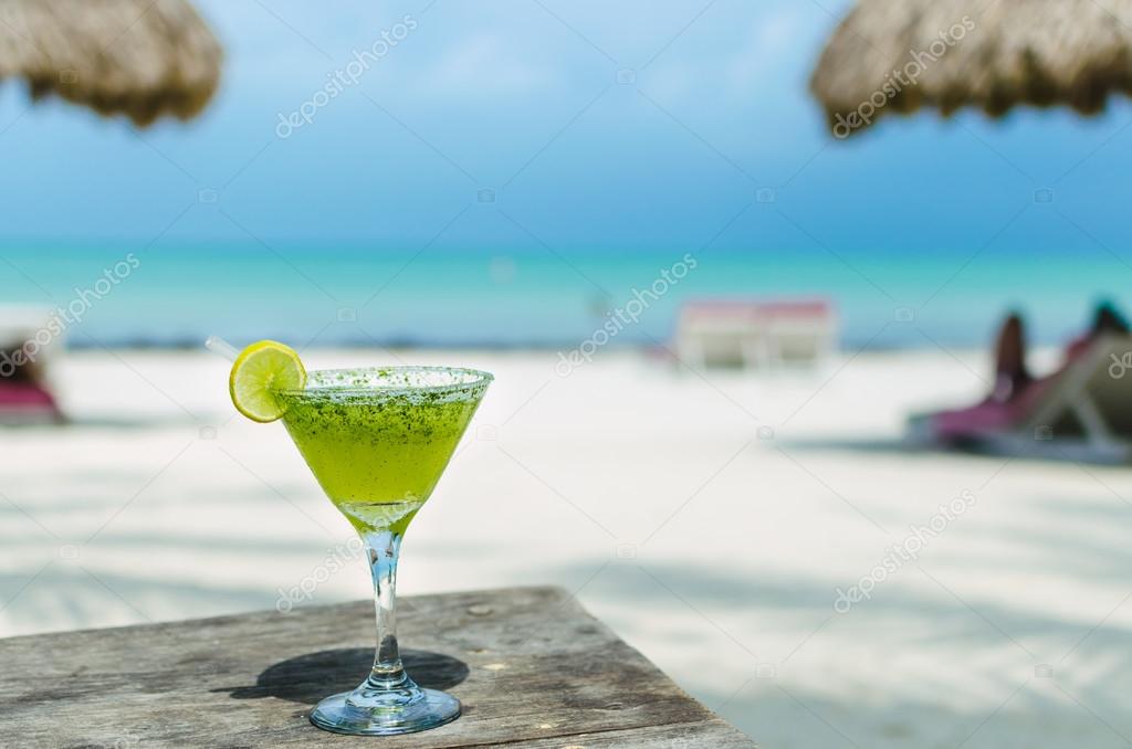 Fresh Margarita cocktail on a table at tropical white sandy beach in the Caribbean sea