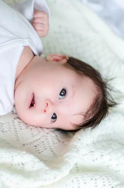 Милая маленькая дочка на белом шерстяном одеяле — стоковое фото