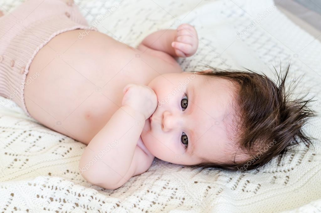 Cute newborn baby girl lying on woolen blanket with a toy