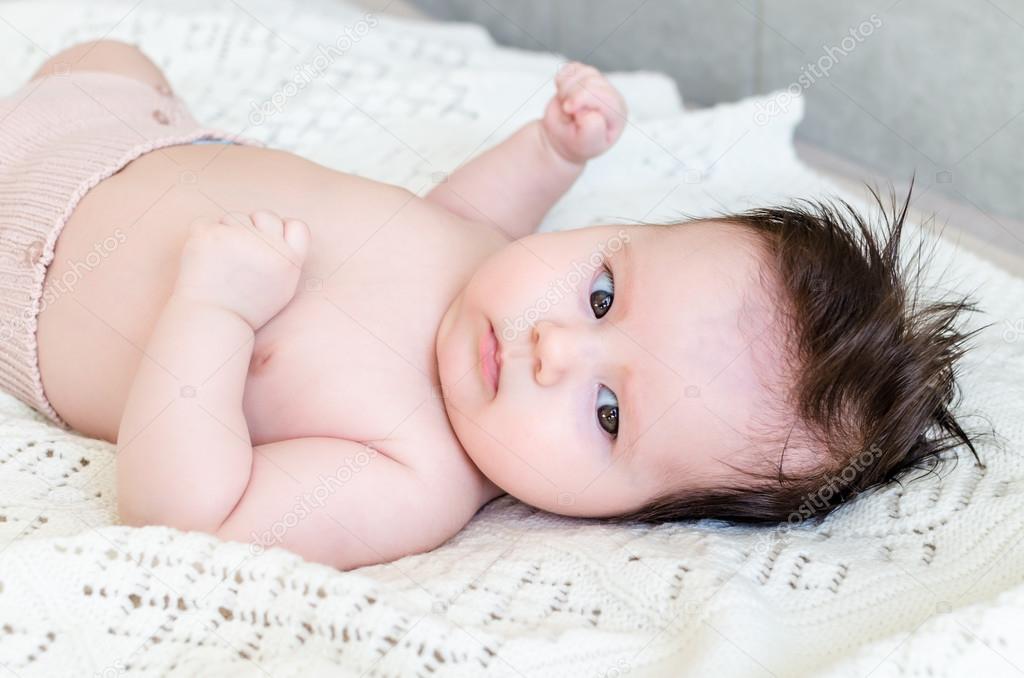 Cute newborn baby girl lying on woolen blanket with a toy