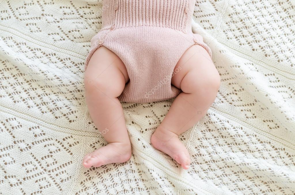 Tiny little newborn baby's feet in woolen shorts