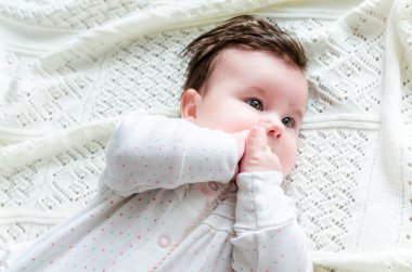 Cute newborn baby girl in romper suit lying on woolen blanket