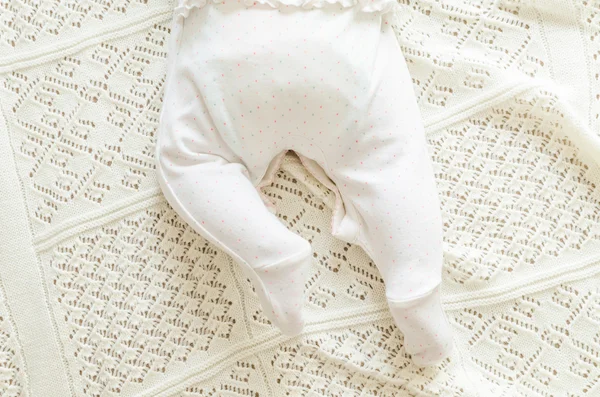 Tiny little newborn baby's feet in spotted romper suit on woolen — Stock fotografie