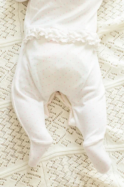 Tiny little newborn baby's feet in spotted romper suit on woolen — Stock fotografie