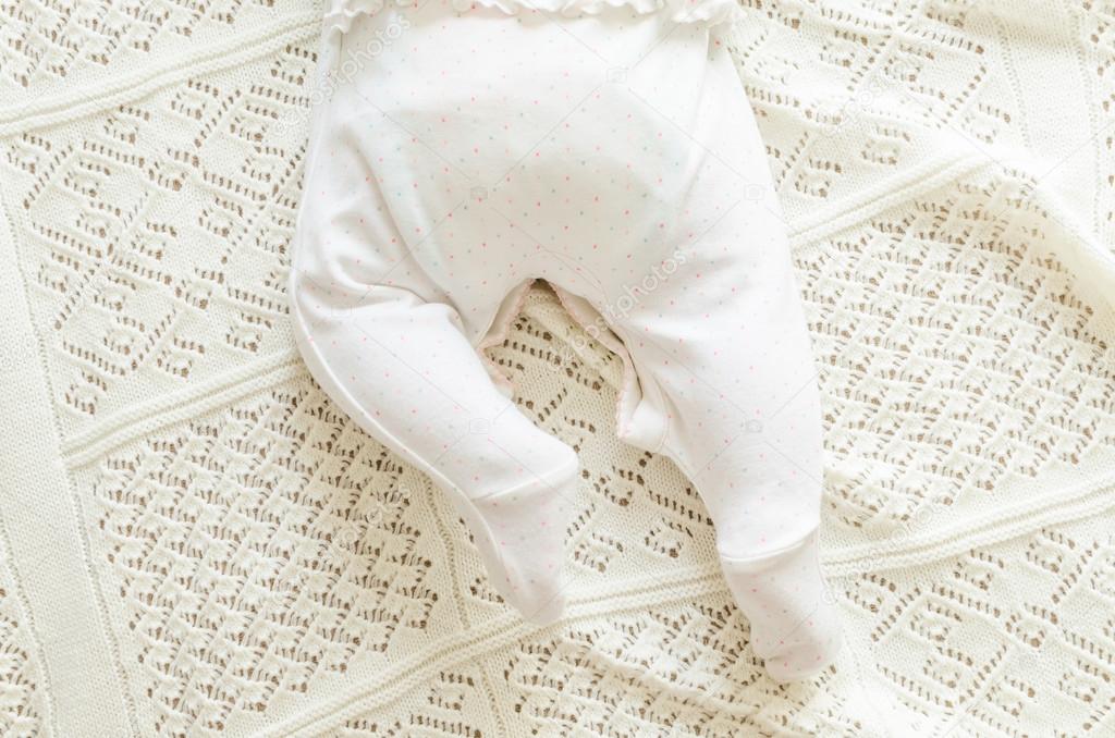 Tiny little newborn baby's feet in spotted romper suit on woolen