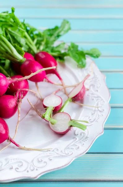 A bunch of fresh radish on plate over rustic wooden turquoise table background — Stockfoto