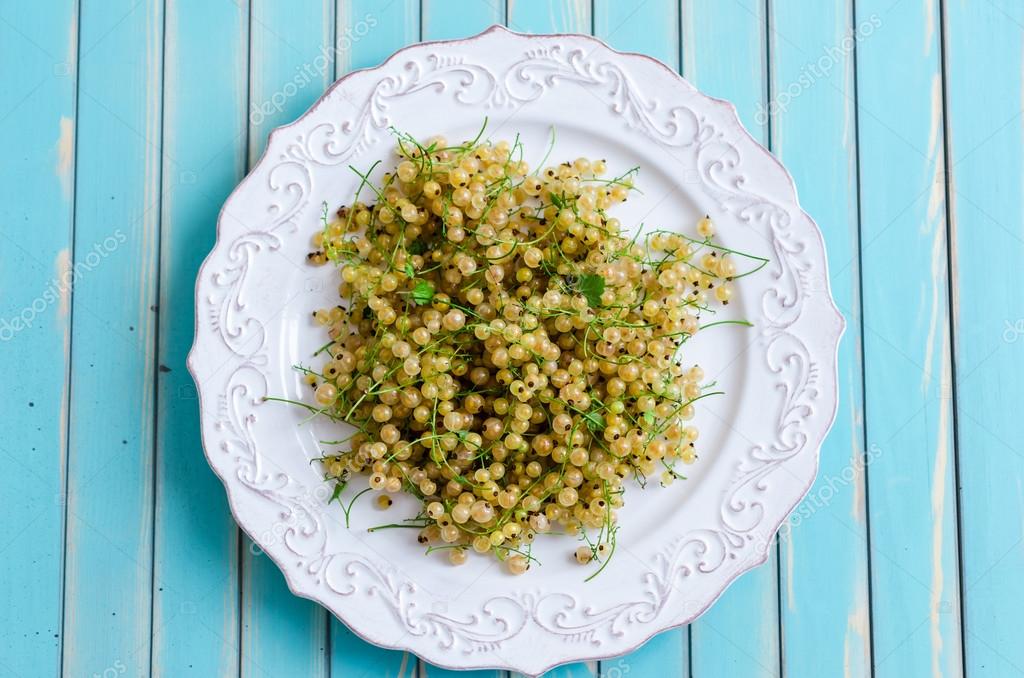 Fresh white currant on plate on rustic wooden turquoise table background